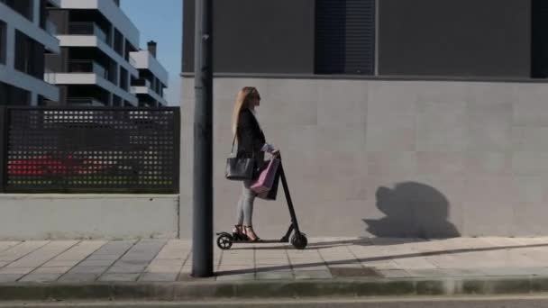 Mujer llegando a casa en scooter eléctrico — Vídeos de Stock