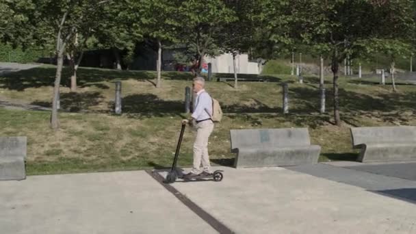 Hombre mayor montando en scooter eléctrico — Vídeos de Stock