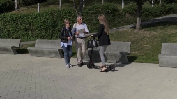 Pareja mayor pidiendo una dirección a una mujer en scooter eléctrico — Vídeos de Stock
