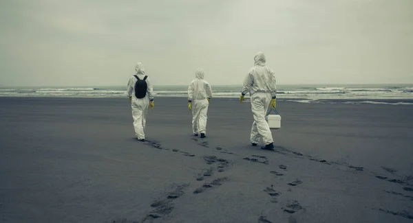 Pessoas com fatos de proteção bacteriológica andando na praia — Fotografia de Stock