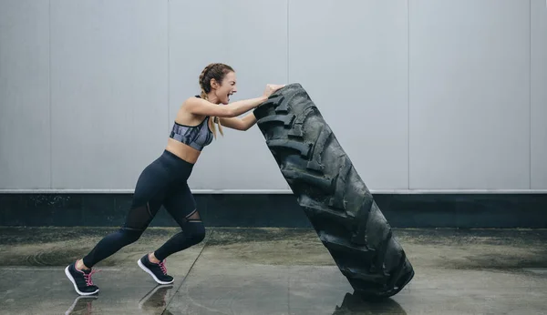 Sportswoman doing cross-training lifting a tire — Stock fotografie