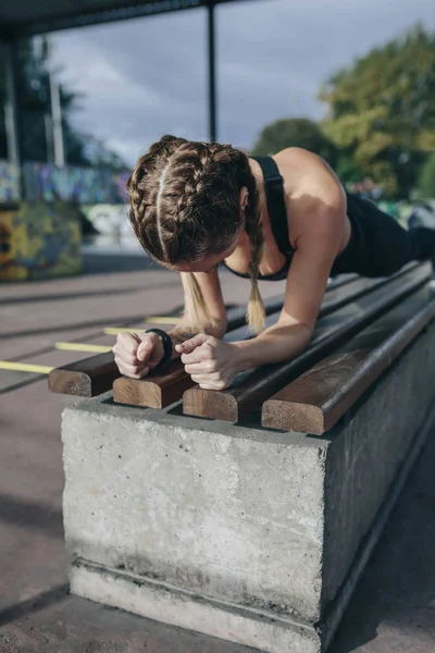 Sportvrouw doet plank op een bank — Stockfoto