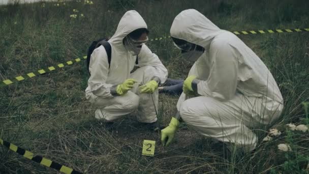 Dva Lidé Bakteriologickou Ochranou Sbírají Důkazy Igelitového Sáčku Vedle Mrtvoly — Stock video