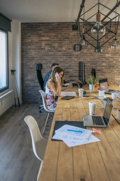 En kvinne som snakker på mobilen på et kontor. – stockfoto