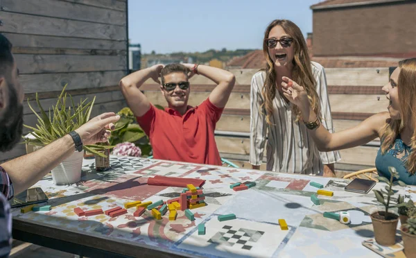 Офисные работники играют с башней на террасе — стоковое фото