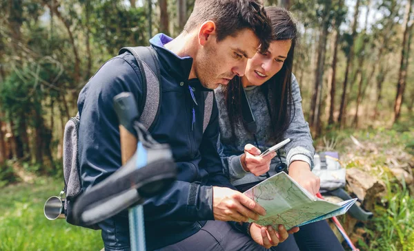 Couple doing trekking sitting looking mobile and map — Stock Photo, Image