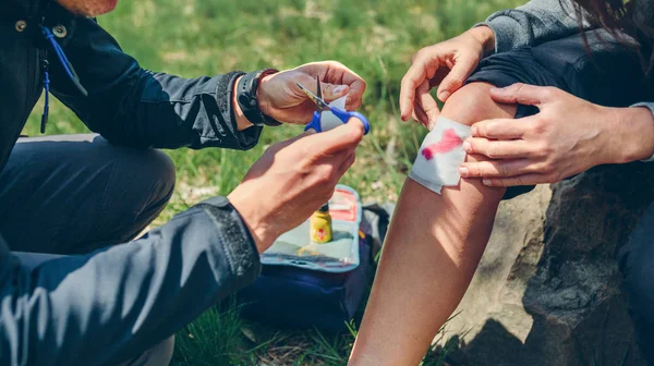 Man healing knee to woman who has been injured trekking — Stock Photo, Image