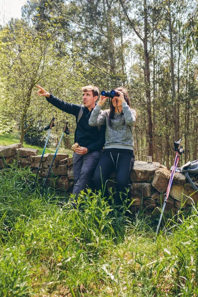 Couple doing trekking looking with binoculars — Stock Photo, Image