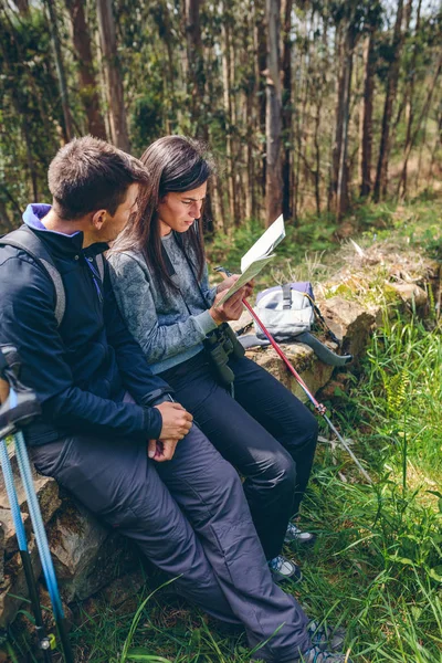 Couple doing trekking sitting looking at a map — Stock Photo, Image