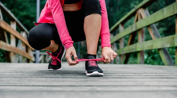Wanita olahragawan yang mengikat tali sepatu bersiap untuk berlari — Stok Foto