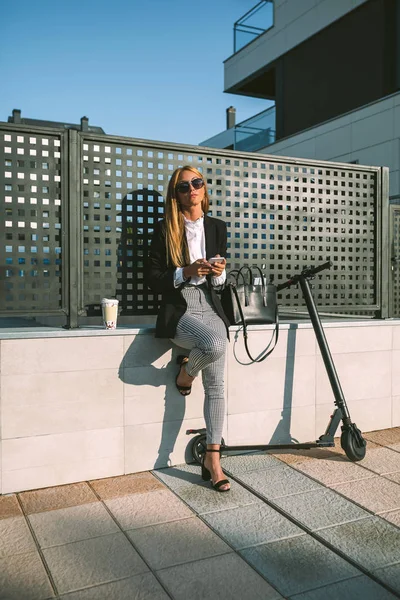 Businesswoman using mobile with her scooter next — Stock Photo, Image