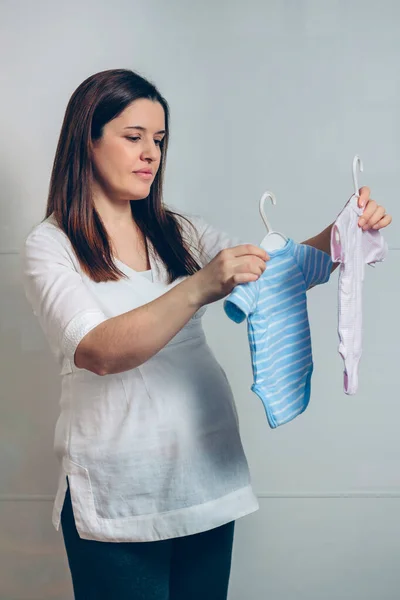 Беременная выбирает детские купальники — стоковое фото