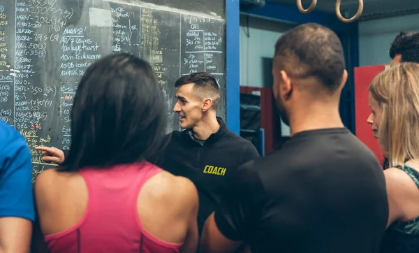 Coach explicando a los atletas en el gimnasio — Foto de Stock