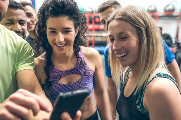 Αθλητές που κοιτάζουν το κινητό ενός συμπαίκτη τους στο γυμναστήριο — Φωτογραφία Αρχείου