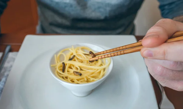 Man eating spaghetti and crickets — Stock Photo, Image