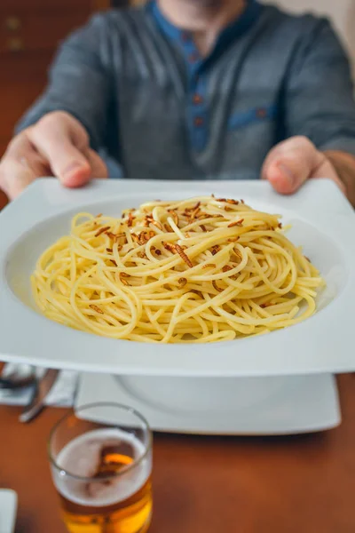 Mani d'uomo che mostrano spaghetti con piatto di vermi — Foto Stock