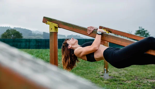 Sportvrouw training opknoping op een houten bar — Stockfoto