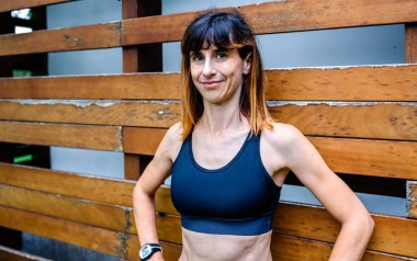 Ahşap arka planda neşeli bir bayan atlet.