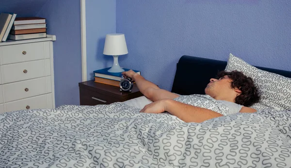 Young man stopping the alarm clock — Stock Photo, Image