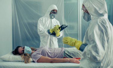Bakteriyolojik korumalı doktorlar virüs bulaşmış bir hastayı inceliyor.
