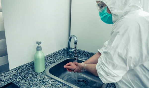 Vrouw in bacteriologische bescherming pak handen wassen — Stockfoto