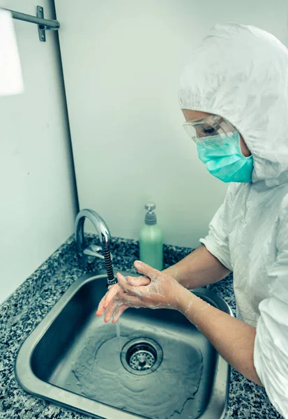 Mujer en traje de protección bacteriológica lavándose las manos — Foto de Stock