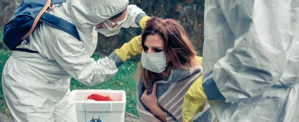 Médicos poniendo máscara protectora en la mujer infectada con un virus — Foto de Stock