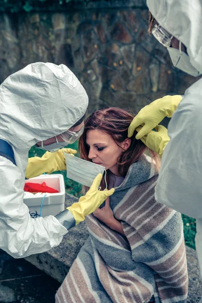 Artsen zetten beschermende masker op vrouw geïnfecteerd met een virus — Stockfoto