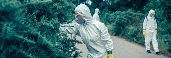 Personas en trajes de protección bacteriológica que buscan muestras en carreteras vacías — Foto de Stock