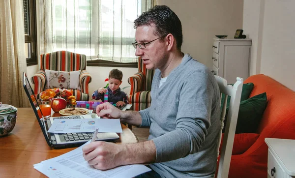 Padre trabajando en casa mientras su hijo juega — Foto de Stock