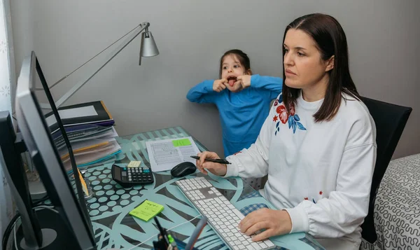 Žena telecomuting dělat videokonferenci se svou dcerou šklebí za — Stock fotografie