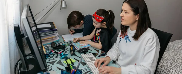 Mujer teletrabajando con sus hijos haciendo la tarea — Foto de Stock