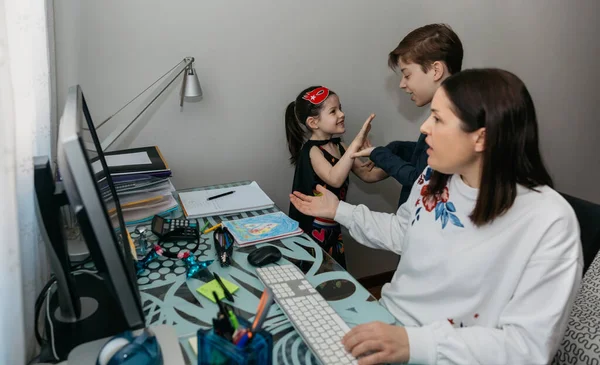 Mujer trabajando desde casa con sus hijos molestándola — Foto de Stock