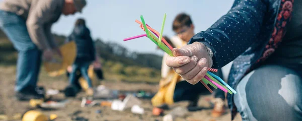 Mujer mostrando un puñado de pajitas recogidas en la playa — Foto de Stock