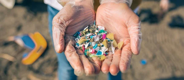Händerna med mikroplast på stranden — Stockfoto