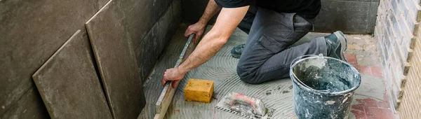 Bricklayer checking floor with a level — Stock Photo, Image