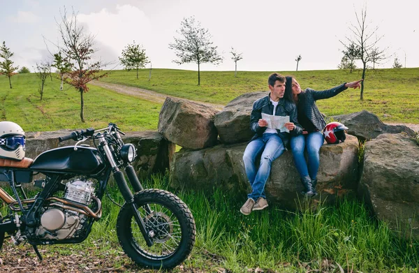 Pareja sentada mirando un mapa con motocicleta — Foto de Stock