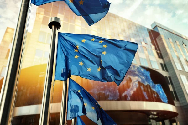 EU zászló integet, Európai Parlament épülete előtt. — Stock Fotó