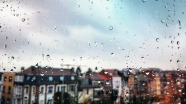 Ön planda yağmur damlalarıyla kaplı Avrupa kentinin çatılarının hızlandırılmış görüntüleri