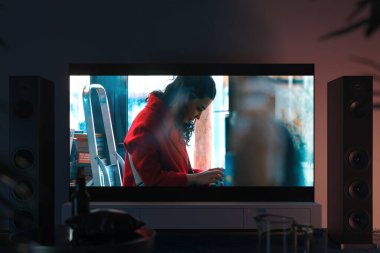 Modern iç dekorasyonda beyaz dolapta film çekilen büyük siyah televizyon seti. Ön görünüm.