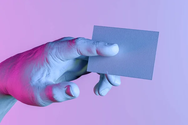 Mano humana blanca sosteniendo la tarjeta de visita en blanco con espacio vacío. Mano iluminada por luces de neón. renderizado 3d — Foto de Stock