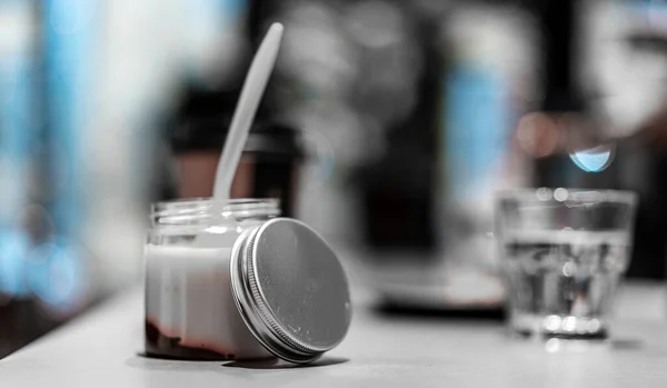 Garrafa de iogurte fresco com colher dentro da mesa no café. Vista lateral — Fotografia de Stock