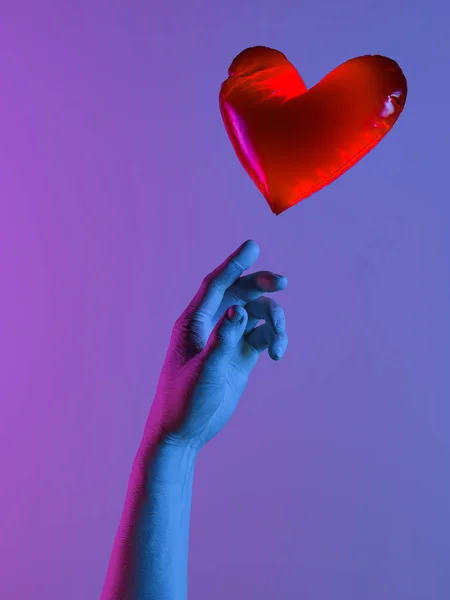Το ανθρώπινο χέρι φωτίζεται με μπλε και ροζ νέον φώτα στέλνοντας μπαλόνι κόκκινη καρδιά. Πρόταση. Έκπληξη. 3d απόδοση. — Φωτογραφία Αρχείου