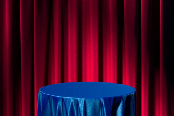 Mesa con paño azul sobre fondo de cortinas rojas. Renderizado 3d —  Fotos de Stock