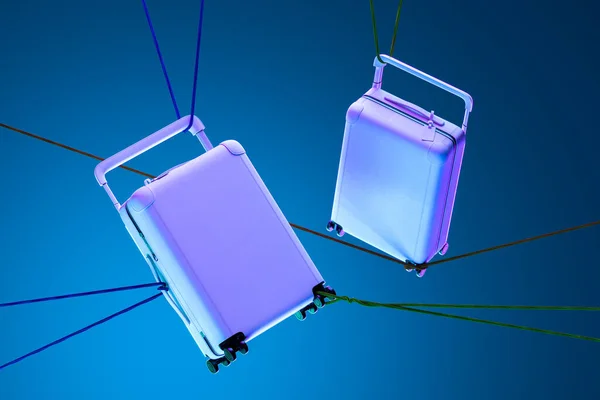 Mavi arka planda iplerle bağlanmış ve neon ışıklarıyla aydınlatılmış Violet Blank Modern Bavulları. 3d Hazırlama — Stok fotoğraf