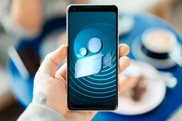 Nahaufnahme eines Mannes, der ein modernes Handy in der Hand hält, mit einer App zum Anschauen von Online-Filmen. Film- oder Kino-Ikone am Bildschirm. 3D-Darstellung — Stockfoto