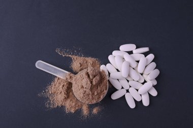 Siyah arka planda spor beslenmesi. Protein ve diyet takviyeleri tozda ve tabletlerde. Metin için boş alan. Boşluğu kopyala