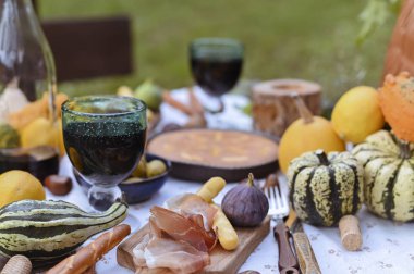 Parkta sonbahar pikniği. Balkabağı, turta, jambon ve aperatif. Ahşap bir masada bir şişe şarap ve bardak. Güneşli bir gün ve açık hava eğlencesi.