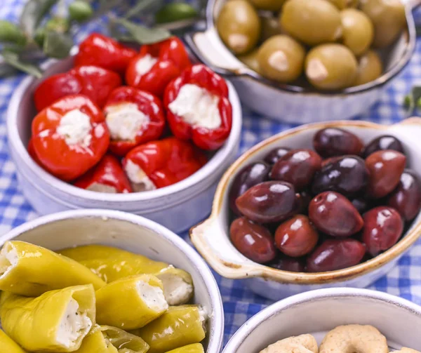 Traditionelle Vorspeisen, grüne und rote Oliven aus der griechischen Küche. Frische Olivenzweige. Kopierraum. Blau karierte Tischdecke. — Stockfoto