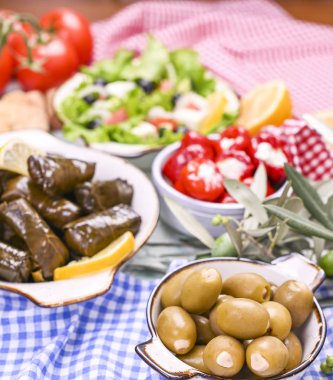 Geleneksel Yunan mutfağı. Üzüm yapraklarına sarılmış pirinç. Limonlu, baharatlı ve Yunan salatalı Dolma. Ev yemeği. Zeytin dalları ve çeşitli baharatlı aperatifler.
